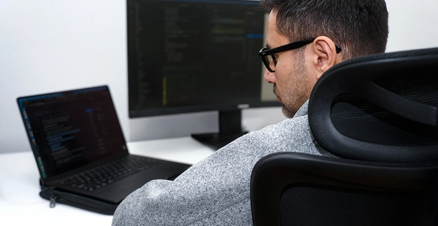Person arbeitet an einem Computer mit Programmcode auf dem Bildschirm