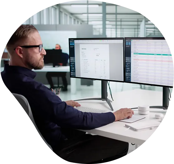 Backend Developer an seinem Arbeitsplatz in einem Großraumbüro