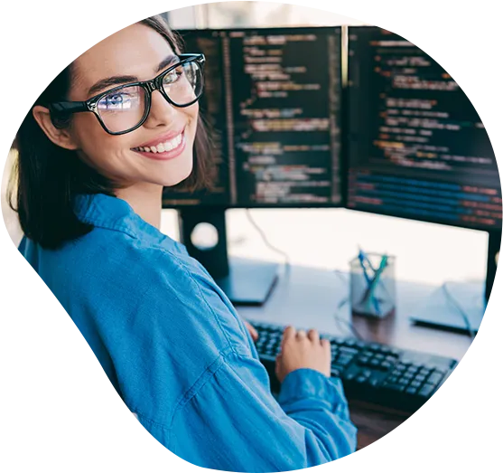 Eine freundliche Mitarbeiterin lächelt vor ihrem Screen mit Code in die Kamera