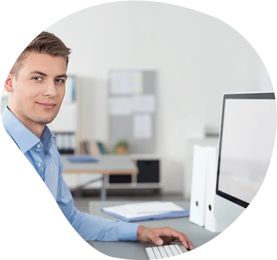 Ein freundlicher Mitarbeiter lächelt an seinem Arbeitsplatz in die Kamera