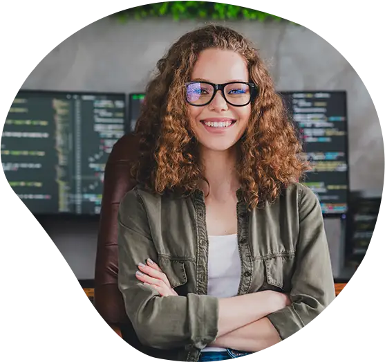 Eine Mitarbeiterin lächelt vor Ihrem Arbeitsplatz in die Kamera