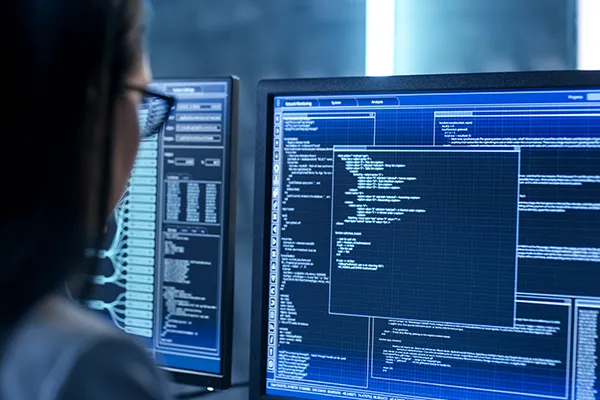 Eine Developerin schaut auf einen Monitor mit Codezeilen