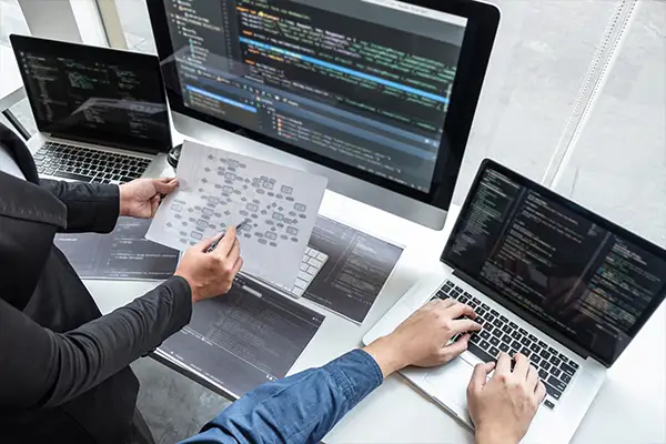 Eifrige Developer diskutieren über einem Projekt vor ihren Monitoren