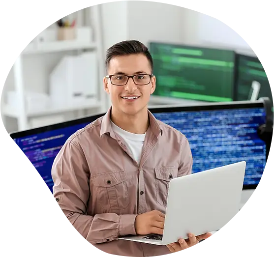 Ein Developer mit Laptop und Monitoren im Hintergrund schaut freundlich in die Kamera