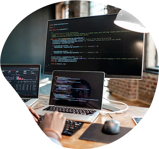 Eine Person programmiert vor Laptop und Monitor