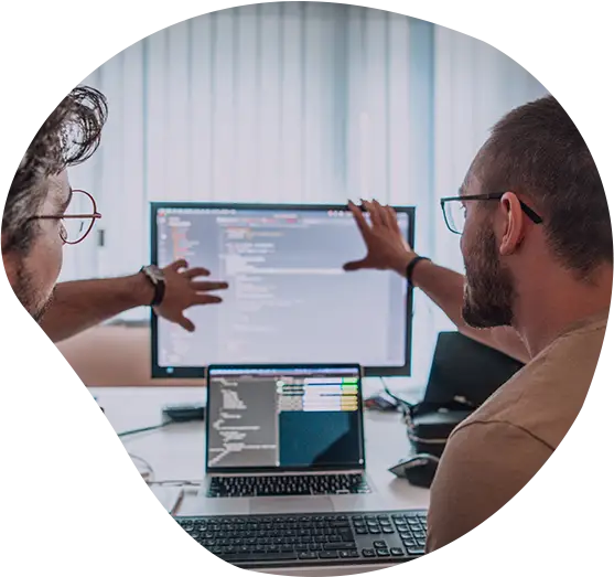 Zwei Personen diskutieren vor einem Bildschirm mit Code