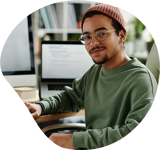 Ein Developer lächelt an seinem Arbeitsplatz freundlich in die Kamera