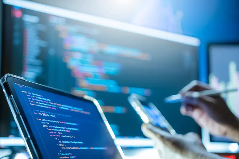 Stifteingabe auf einem Smartphone vor Monitoren