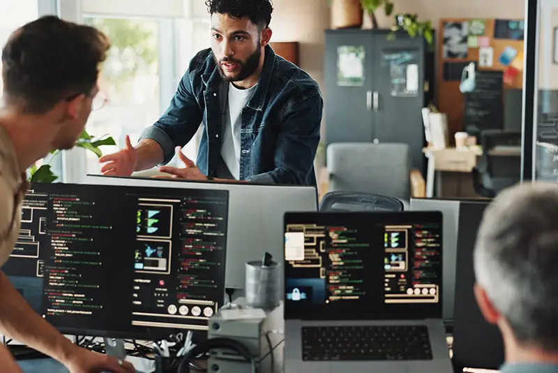 Kollegen besprechen sich über ihre Bildschirme hinweg