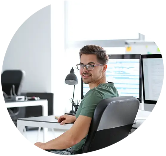 Ein Angestellter schaut vom Arbeitsplatz am Fenster in die Kamera