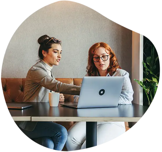 Eine Angestellte zeigt einer Kollegin etwas auf einem Laptop