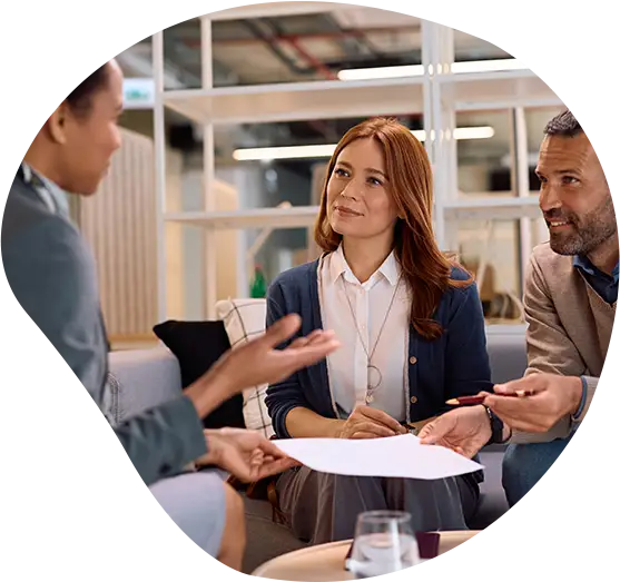 Drei Mitarbeiter*Innen in einem Unternehmen bei einer Besprechung