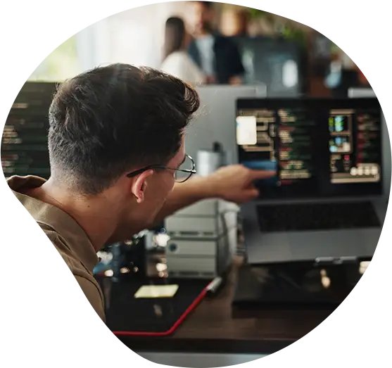 Ein Software Developer zeigt auf Code auf seinem Bildschirm