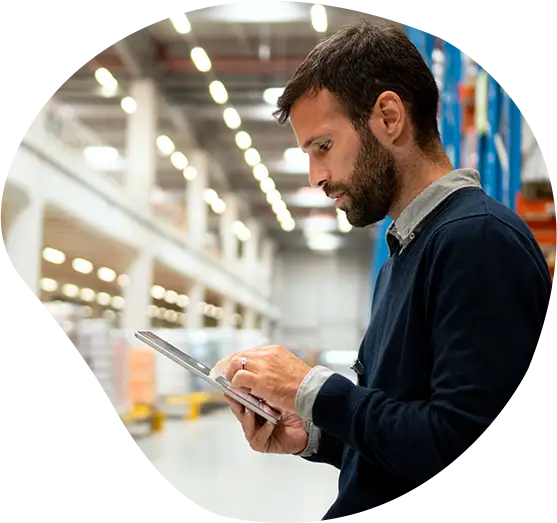 Ein Logistiker steht mit Tablet in einem Lager