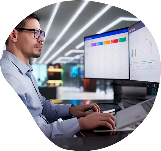 Ein Mann sitzt vor seinen Bildschirmen an seinem Arbeitsplatz