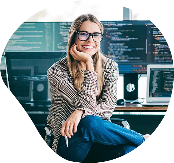 Frau lächelt an ihrem Arbeitsplatz mit mehreren Bildschirmen.