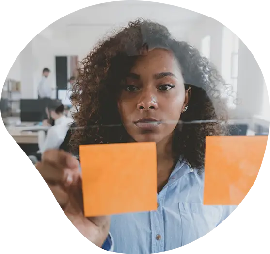 Frau klebt mehrere Zettel an eine Glaswand