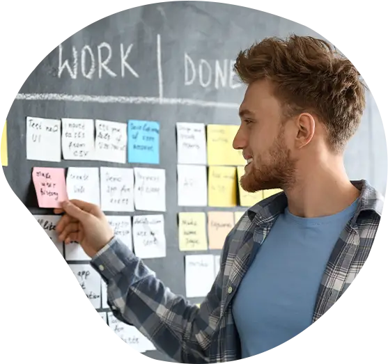 Junger Mann neben einem Scrum-Taskboard im Büro.