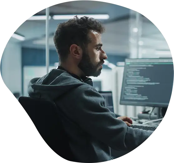 Ein Softwareentwickler sitzt vor einem Bildschrim an seinem Arbeitsplatz.