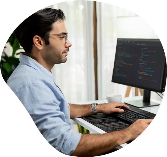 Mann sitzt an seinem Arbeitsplatz und programmiert.