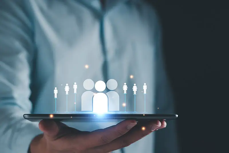 Verschiedene Icons von Personen schweben über einem Tablet