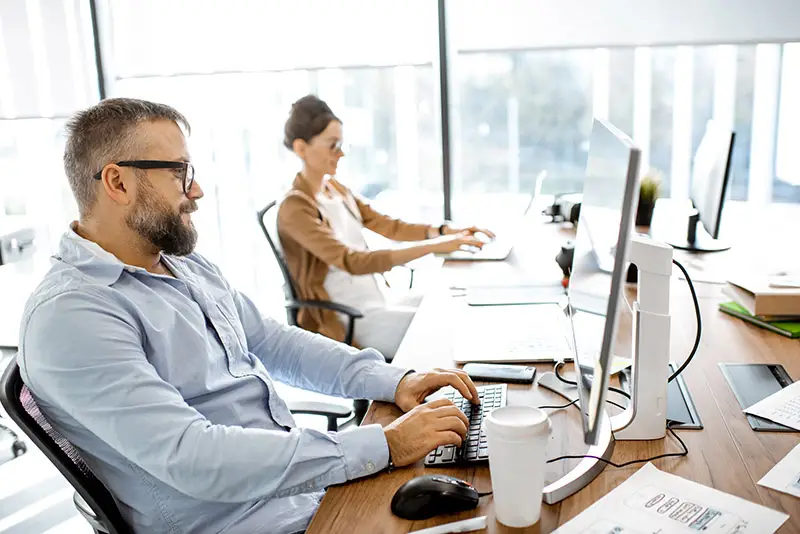 Zwei Mitarbeiter eines Unternehmens bei der Arbeit mit KI-Software