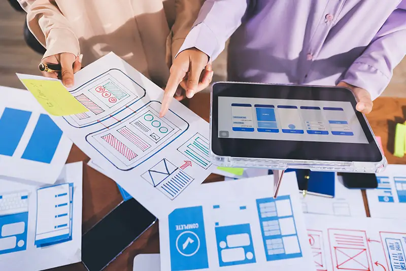 Besprechung von Software-Mockups auf Papier und Tablet