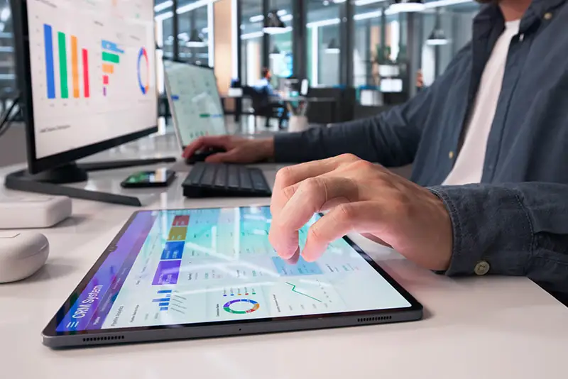 Eine Person arbeitet in einem Großraumbüro an einem Tablet
