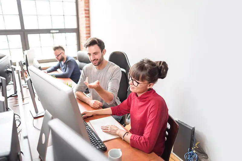 Software-Team bei der Besprechung eines Projekts an ihren Arbeitsplätzen