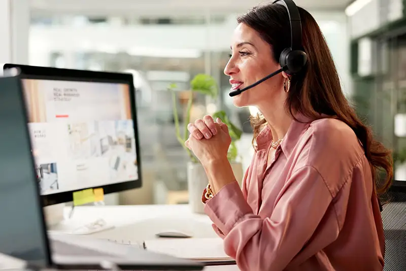 Eine Mitarbeiterin mit Headset an ihrem Computer