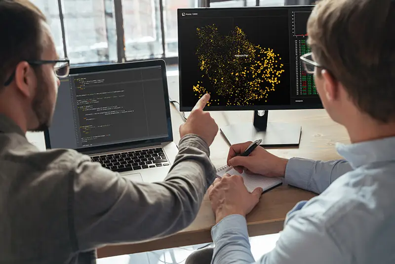 Zwei Mitarbeiter betrachten einen Bildschirm