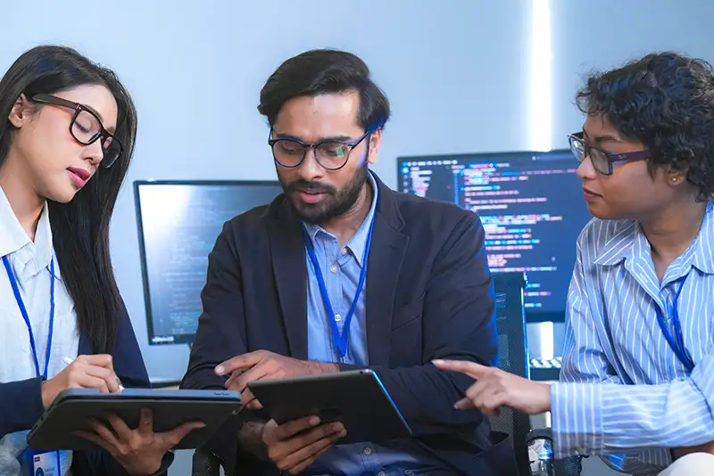 3 Personen besprechen ein Softwareprojekt während sie auf ein Tablet schauen.