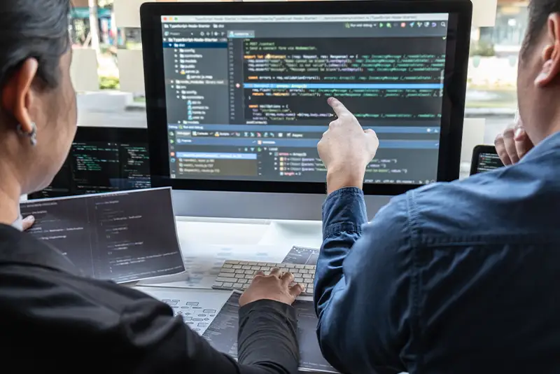 Team von Entwicklerinnen und Entwicklern, das an einem Projekt zur Softwareentwicklung am Computer in einem IT-Unternehmensbüro arbeitet.