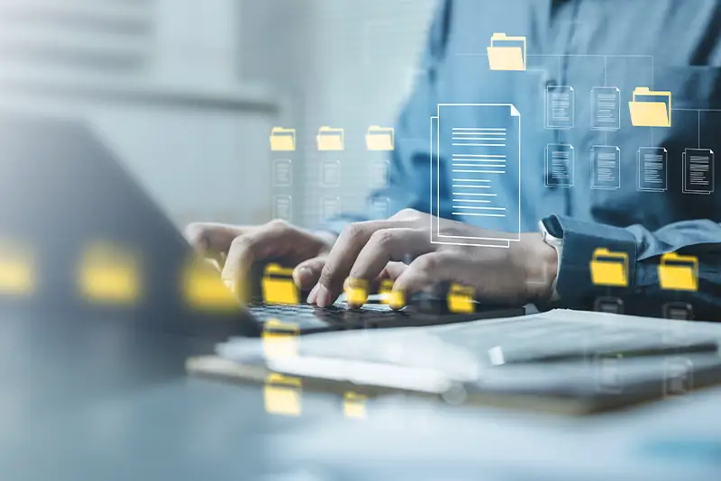 Person sitzt an einem Laptop mit schwebenden Ordner -und Dokumentensymbolen.