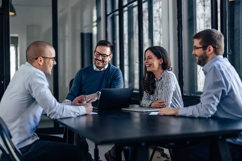 Lachende Programmierer, die in einem Meeting über die Funktion ihrer Software sprechen.