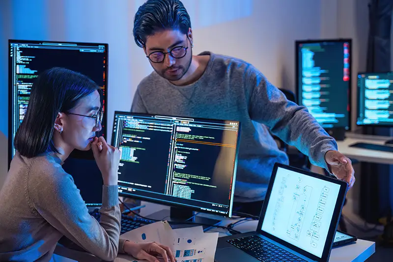 2 Mitarbeiter besprechen ihre Arbeit an einem Arbeitsplatz.