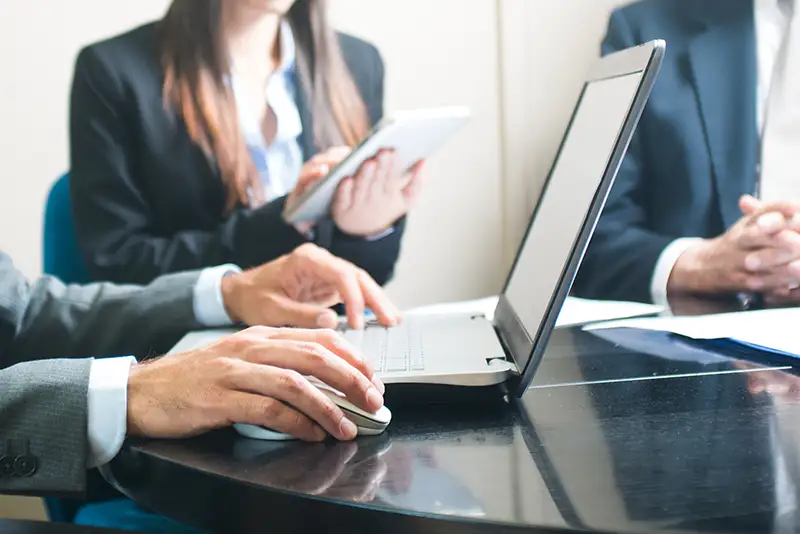 Nahaufnahme mehrerer Personen an einem Tisch in einem Besprechungsraum.
